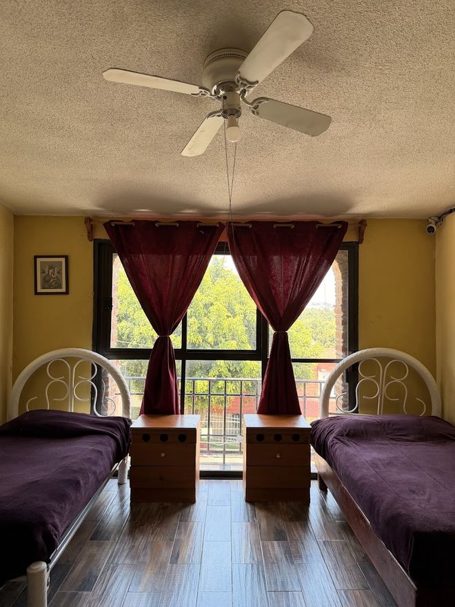Habitación doble con dos camas, burós y una ventana con vista a los árboles