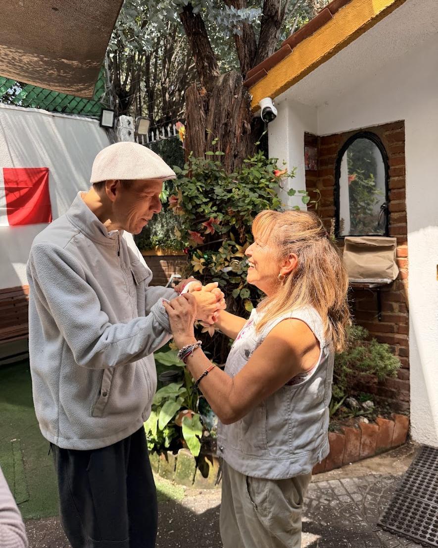 Un señor y una señora bailan sonrientes en el jardín de La Esperanza